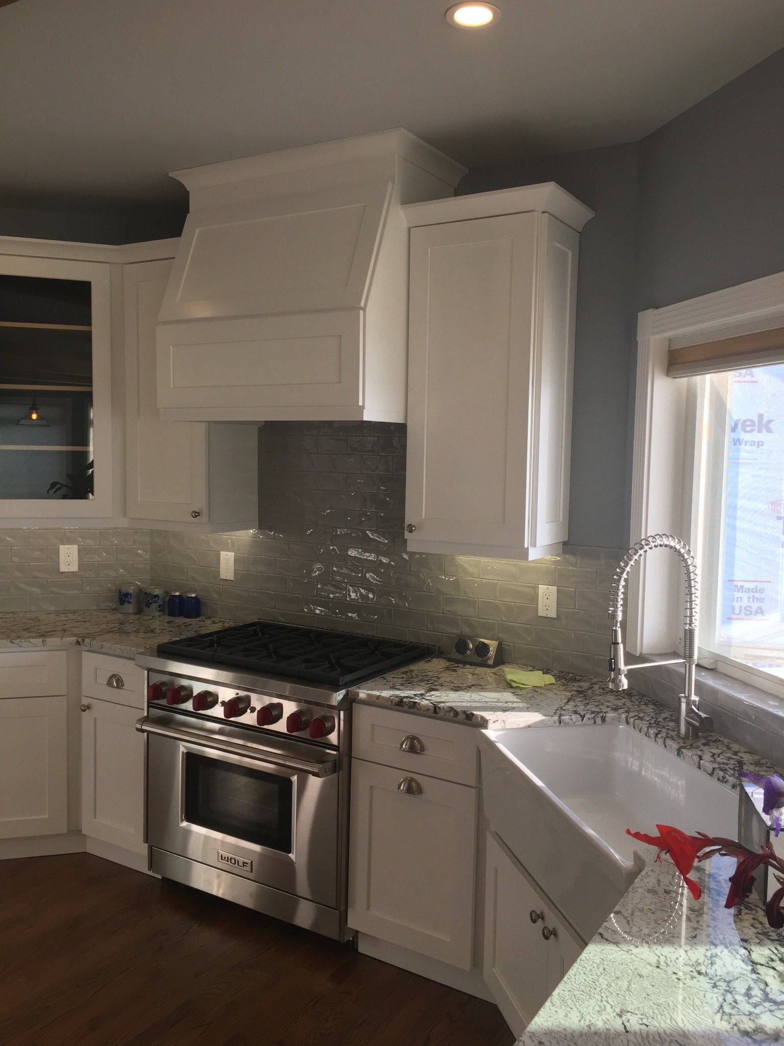 Kitchen cabinets, tile backsplash, countertop, sink, and range after installation