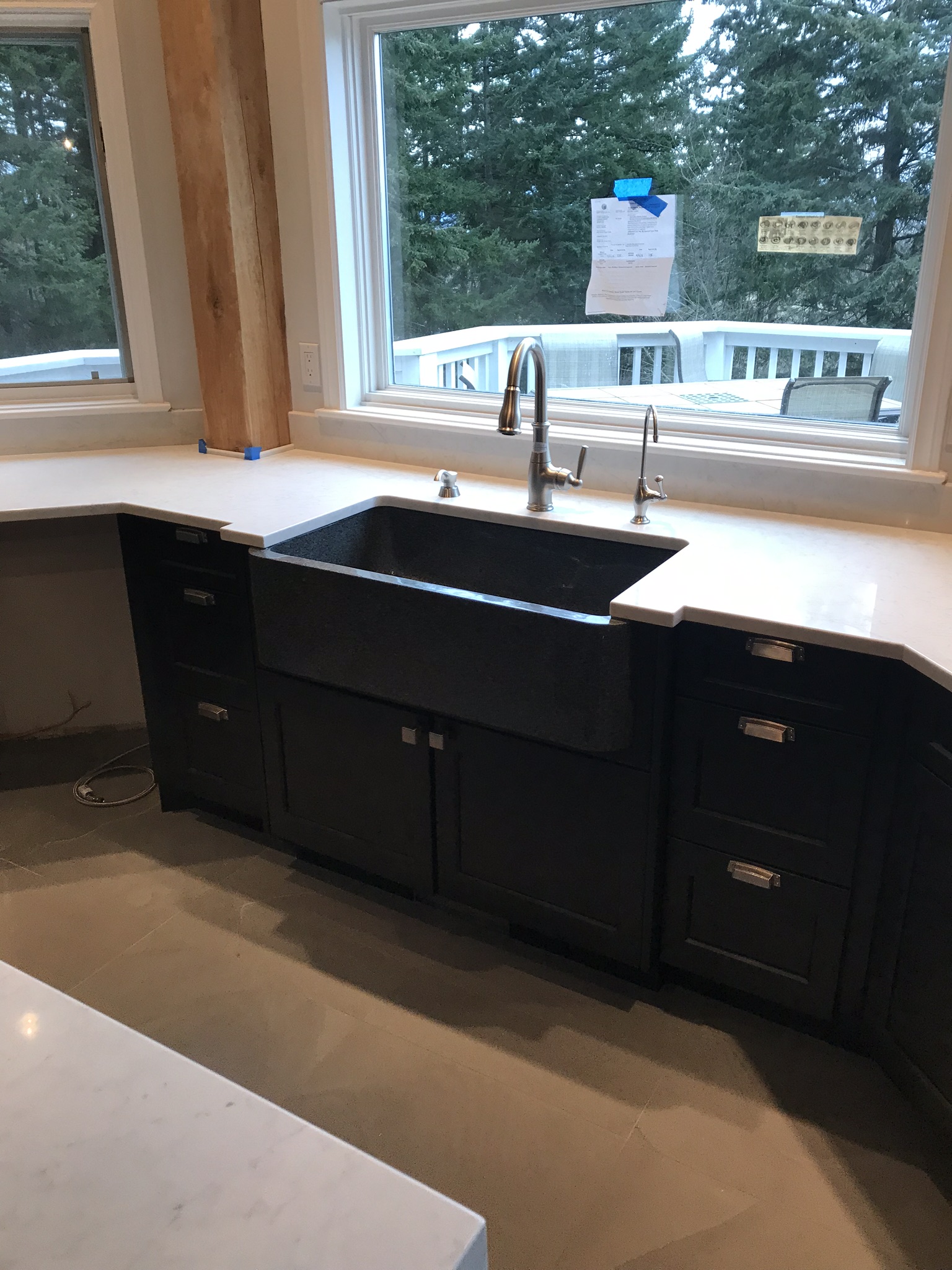 Black apron-front sink beneath a large kitchen window