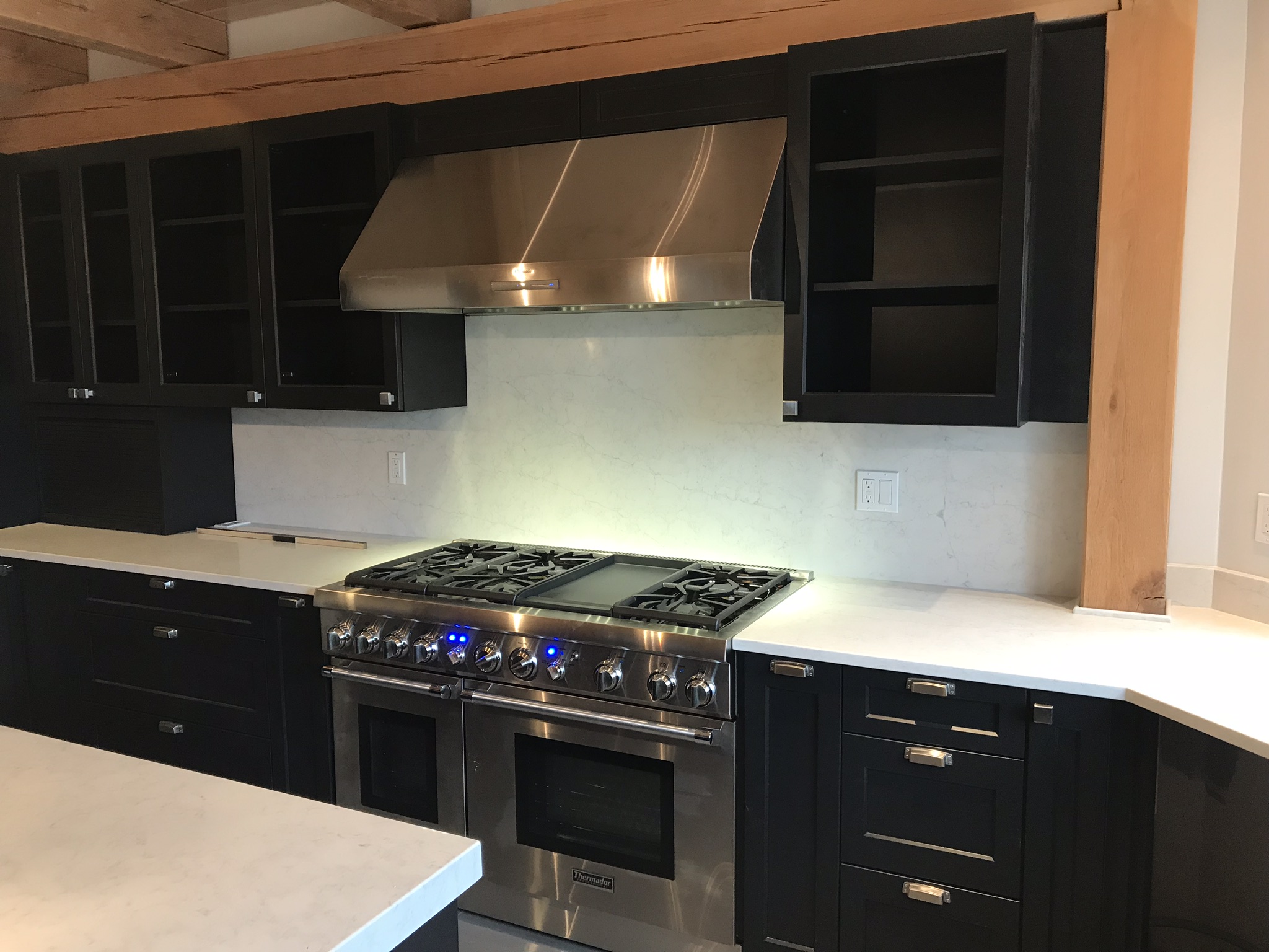 Commercial range and stainless hood framed by black cabinets