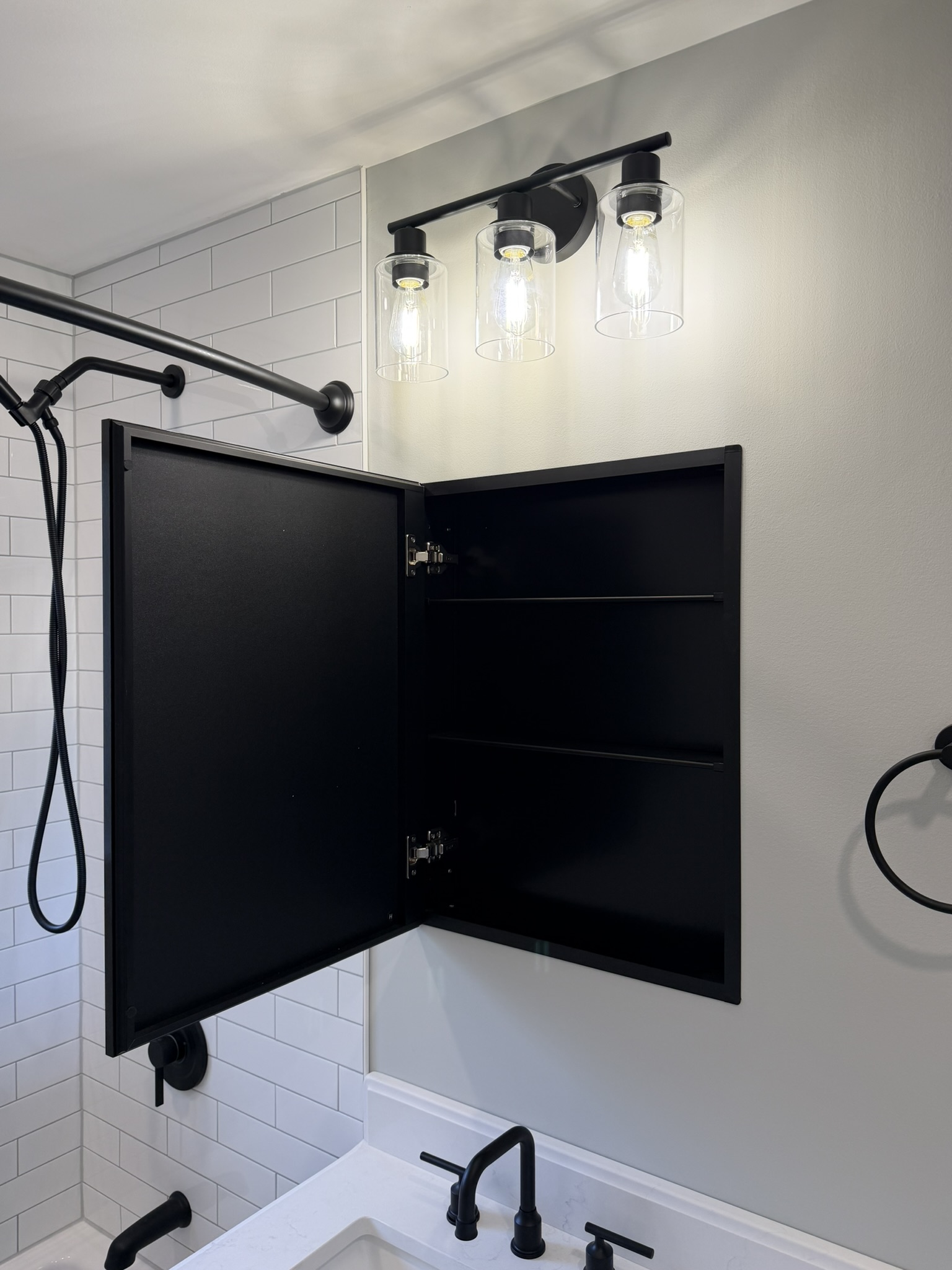 Finished tub surround with black fixtures, recessed niche, and glass light fixture