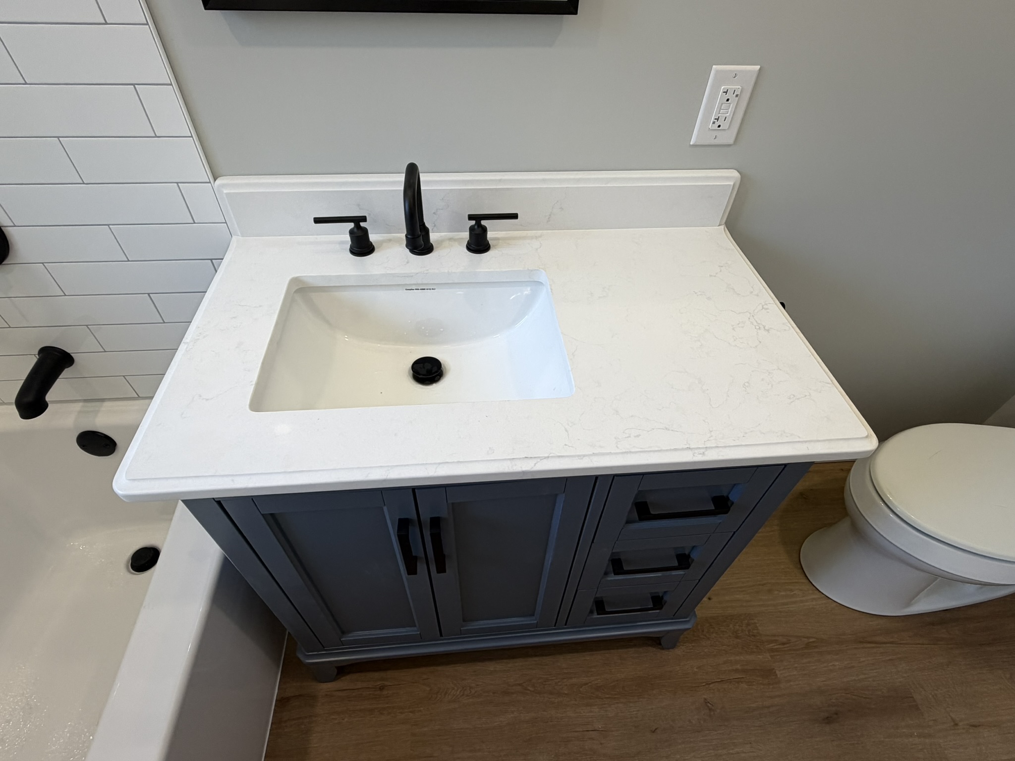 New dark vanity with white countertop and matte black faucet