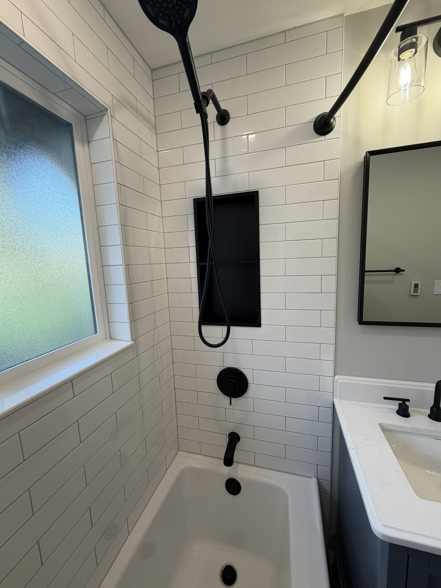 Finished white subway tile surround with matte black shower hardware