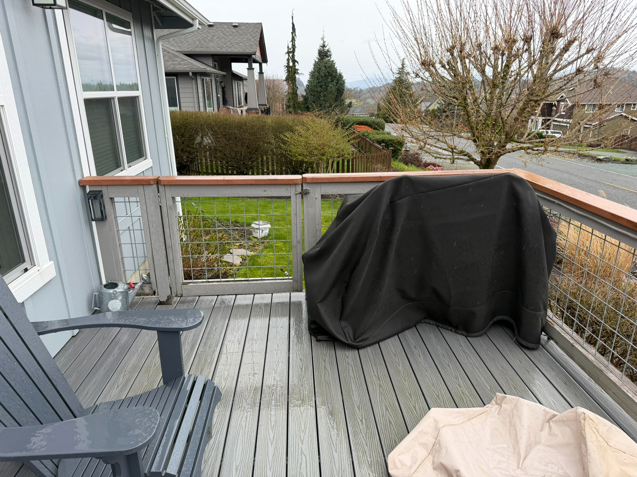 Completed composite deck and cable railing beside the home